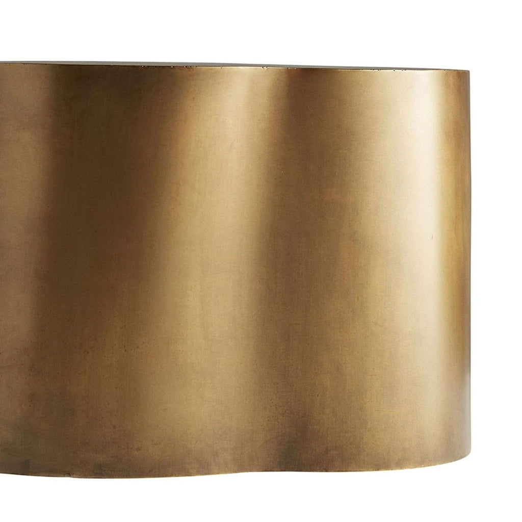 Close-up view of the curved golden lacquered fiberglass base of an Arteriors Home coffee table.