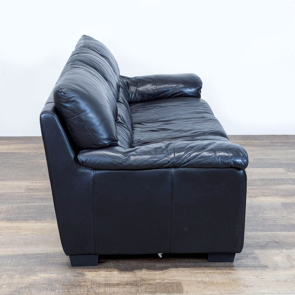 2. Side view of modern Ashley 3-seat sofa featuring soft black leather and generous padded armrests.