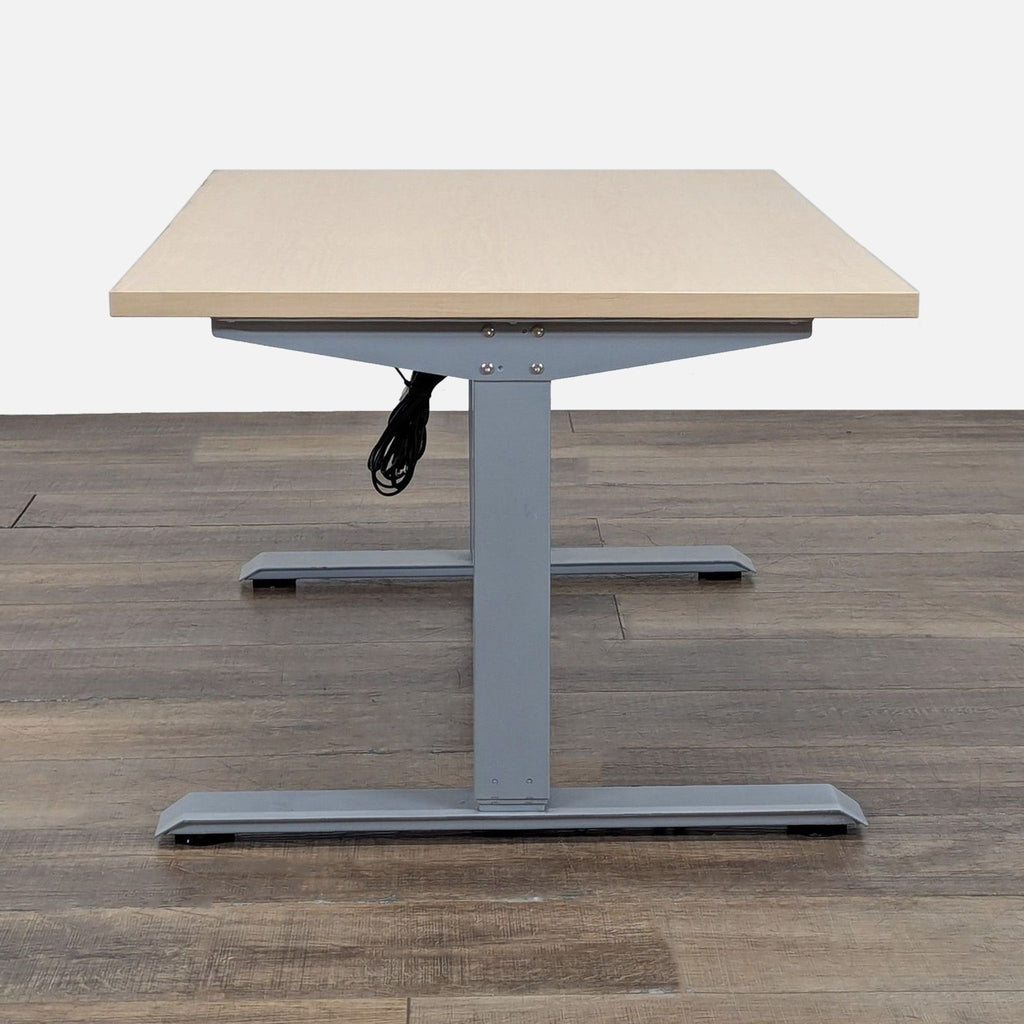 3. Side view of Tüv Rheinland adjustable desk, light wood surface, gray metal base, and visible cords.