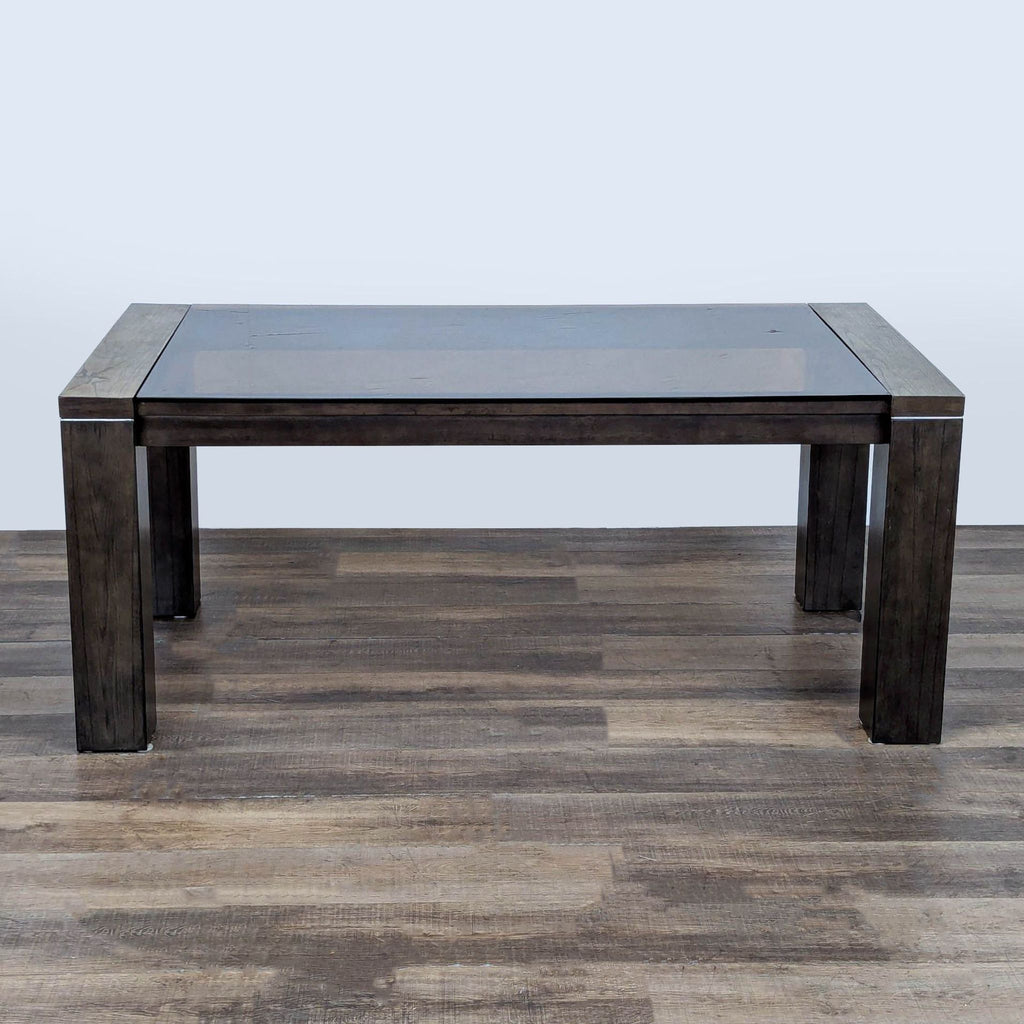 1. Contemporary gray dining table with thick smoked glass top, wide legs, and metal accent bands by Ashley.