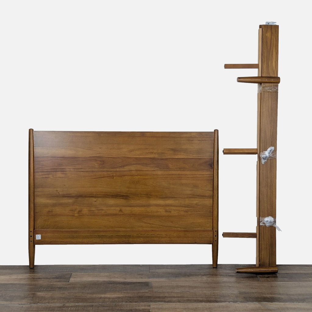 2. Disassembled West Elm acorn wood frame and headboard displayed on a wooden floor.