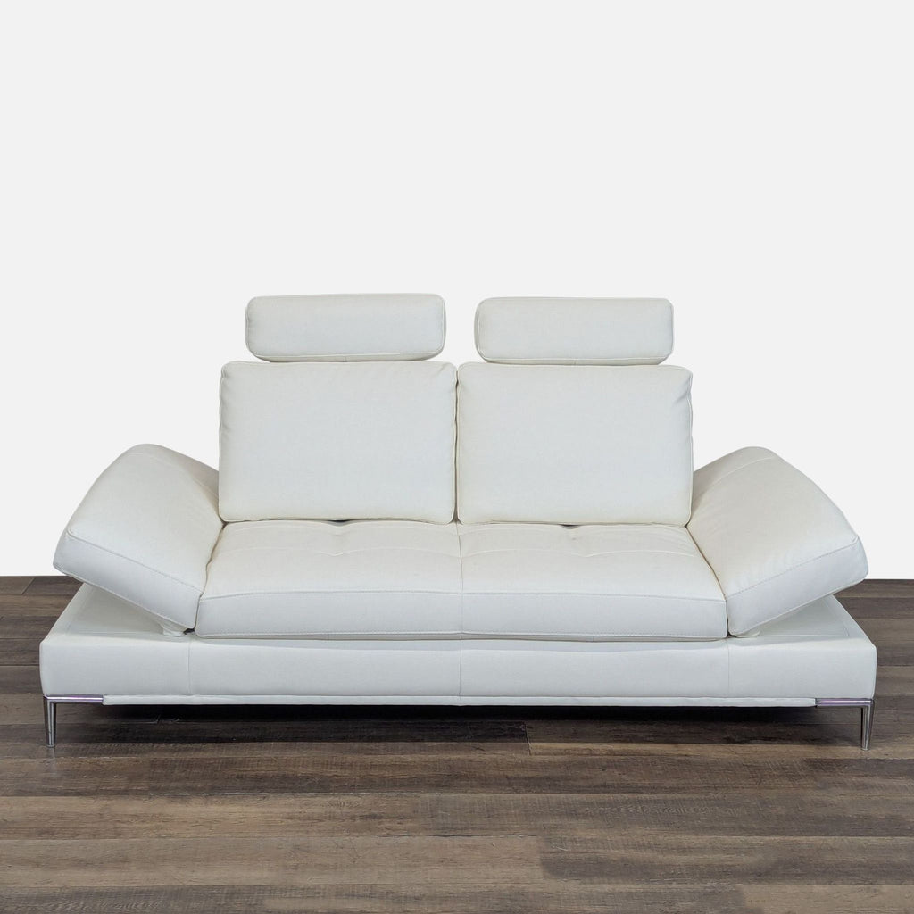 3. White Modani loveseat, low profile, with reclining armrests and upright adjustable leather headrests.