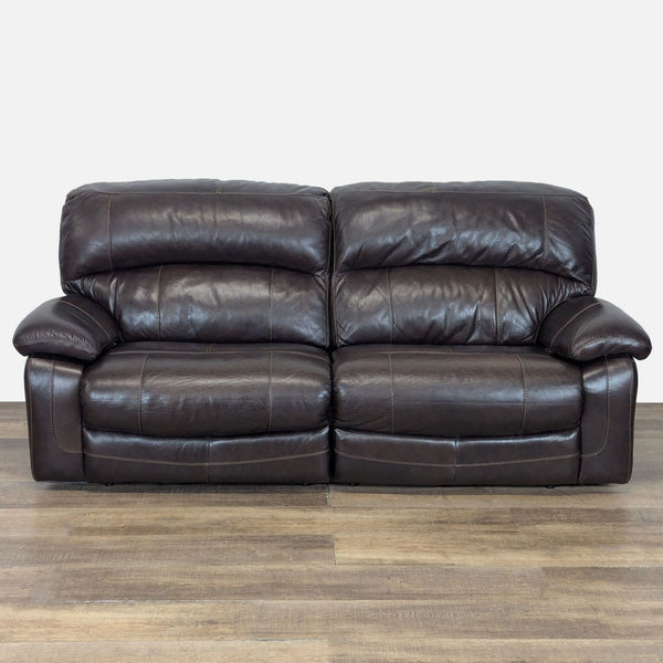 1. Front view of an Ashley Furniture manual reclining loveseat with dark leather upholstery and plush cushions.