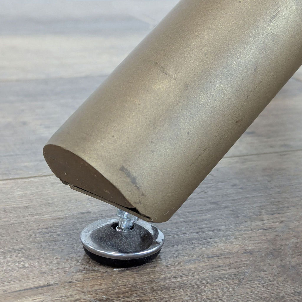 2. Close-up of a Reperch dining table's metal leg with an adjustable floor protector.