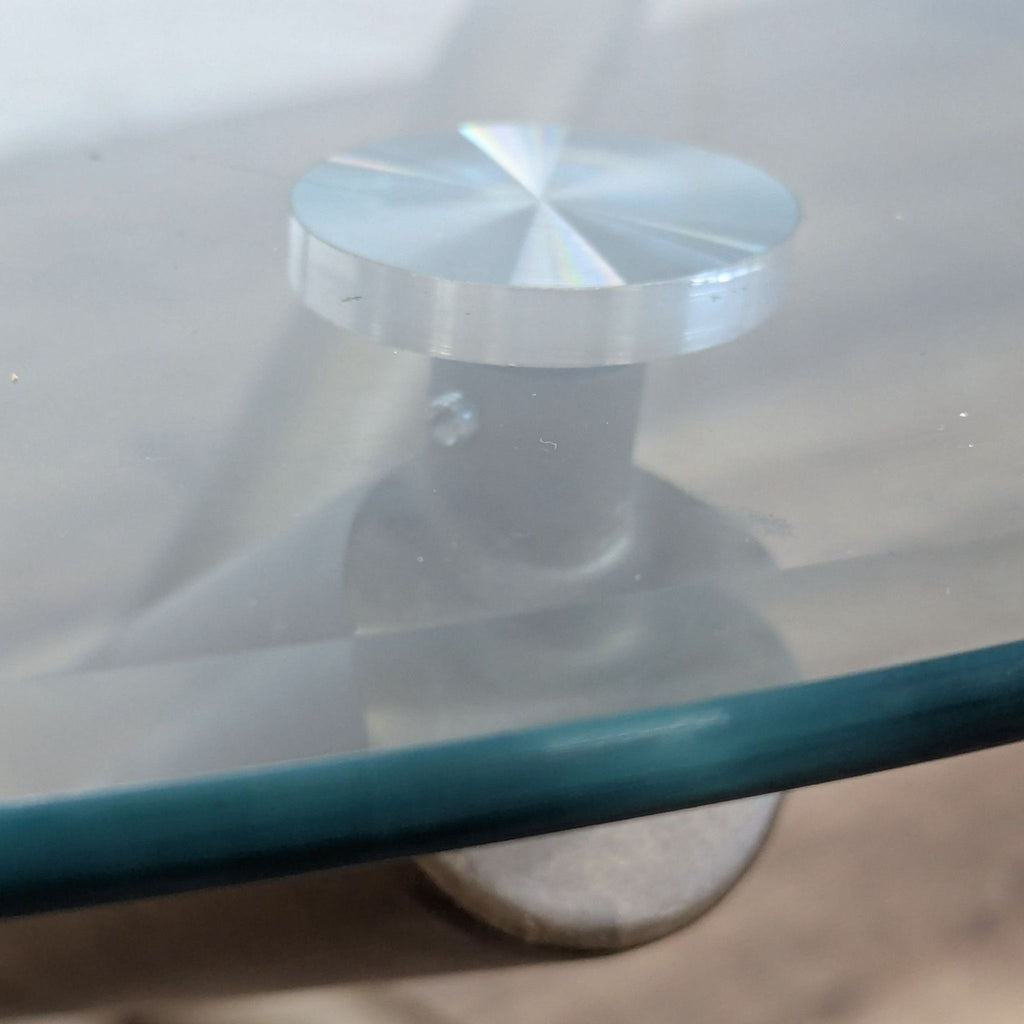 3. Detail view of a Reperch dining table showing the metal connector attaching the glass top to the base.