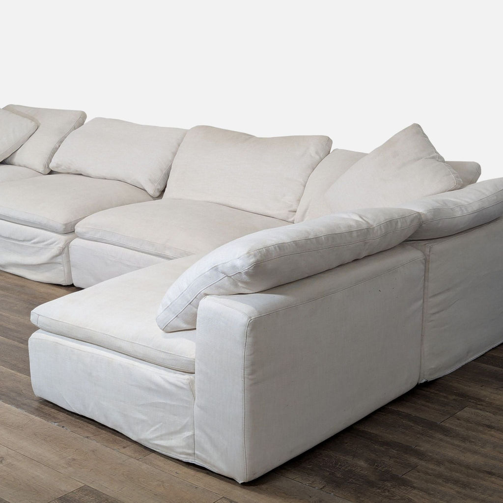 2. Close-up of a plush sectional’s corner seat, showing soft cushions and thick armrest upholstery in beige fabric.