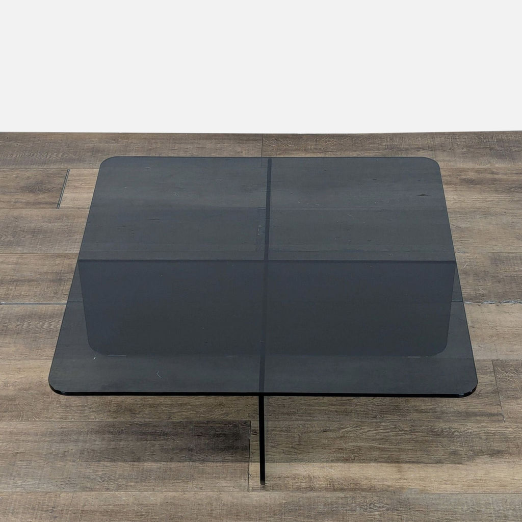 2. Top view of an EQ3 tempered glass coffee table, highlighting its square shape with crossing base panels.
