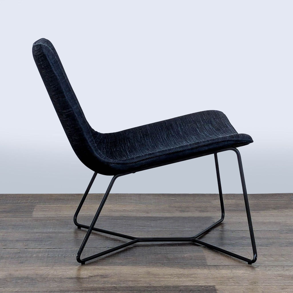 2. Side view of a West Elm lounge chair, showing its wide stance and ergonomic curved design with a steel base.