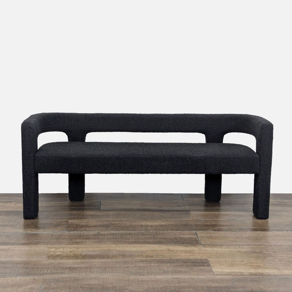 1. Black boucle bench by Caleb Zipperer for CB2, featuring a deep seat and rounded back on wooden floor.