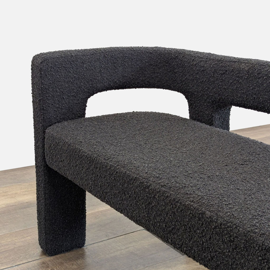 2. Close-up of black boucle bench arm and seat, showing textured, plush upholstery and architectural lines.