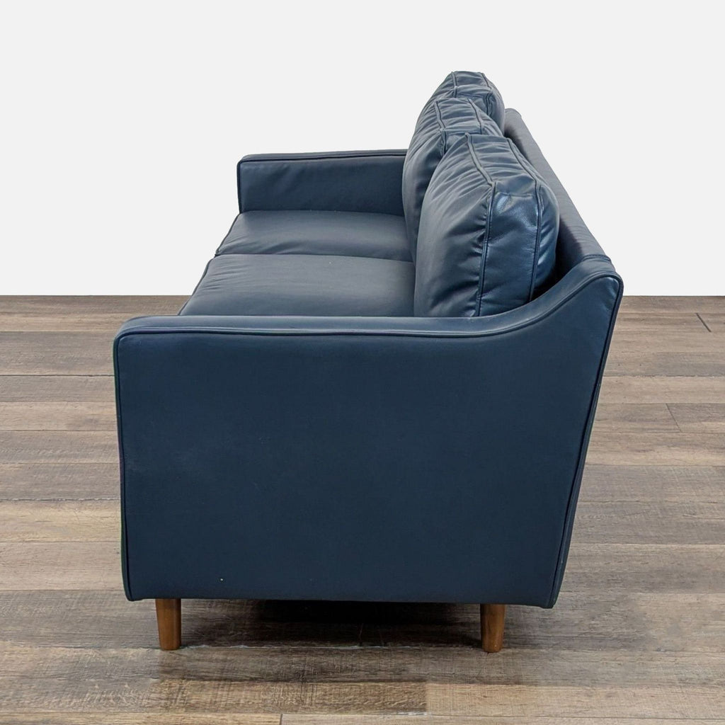 Wayfair 3-seat sofa in navy faux leather, wood feet, shown from the opposite side angle.