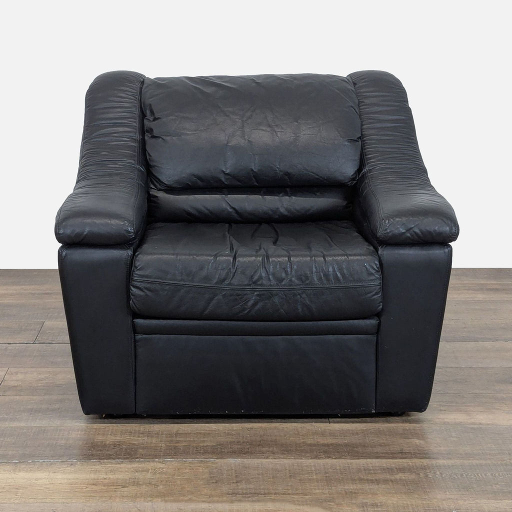 1. Front view of a Krause’s Sofa Factory lounge chair with plush black leather upholstery on wooden flooring.  