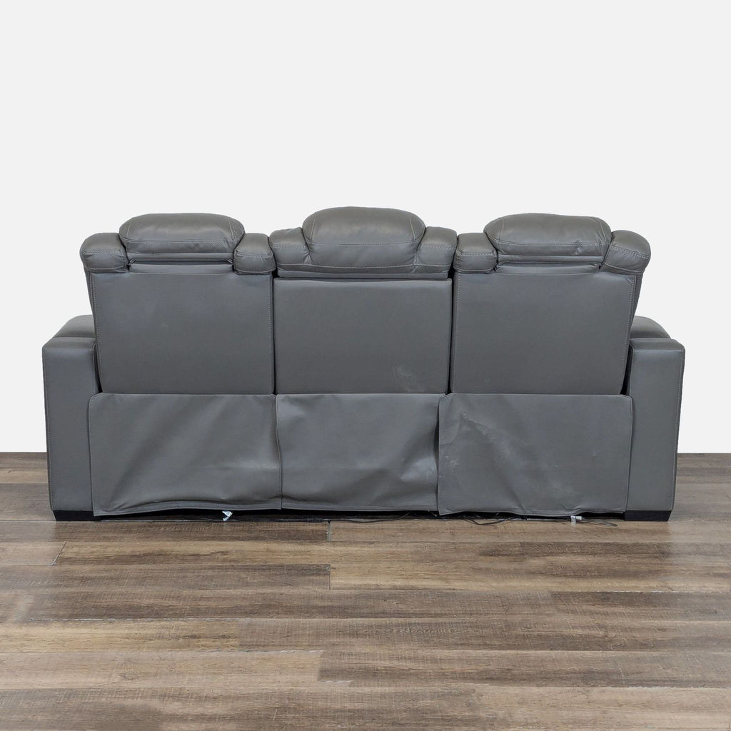 3. Rear view of Ashley 3-seat leather sofa, showing back panels, armrests, and adjustable headrests on a wood floor.
