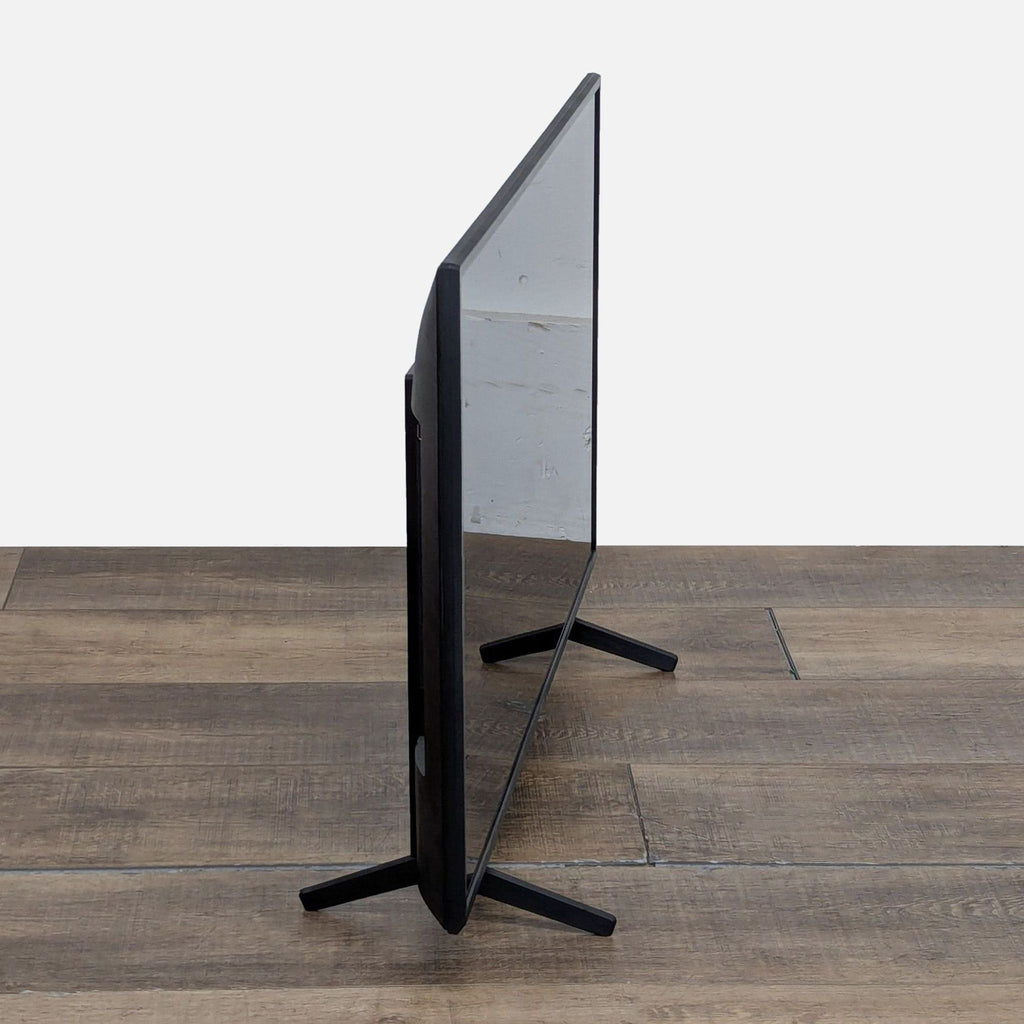 Side profile of a slim Sony KD-43X80J 4K Smart TV showing its thin, modern design on a wooden floor.