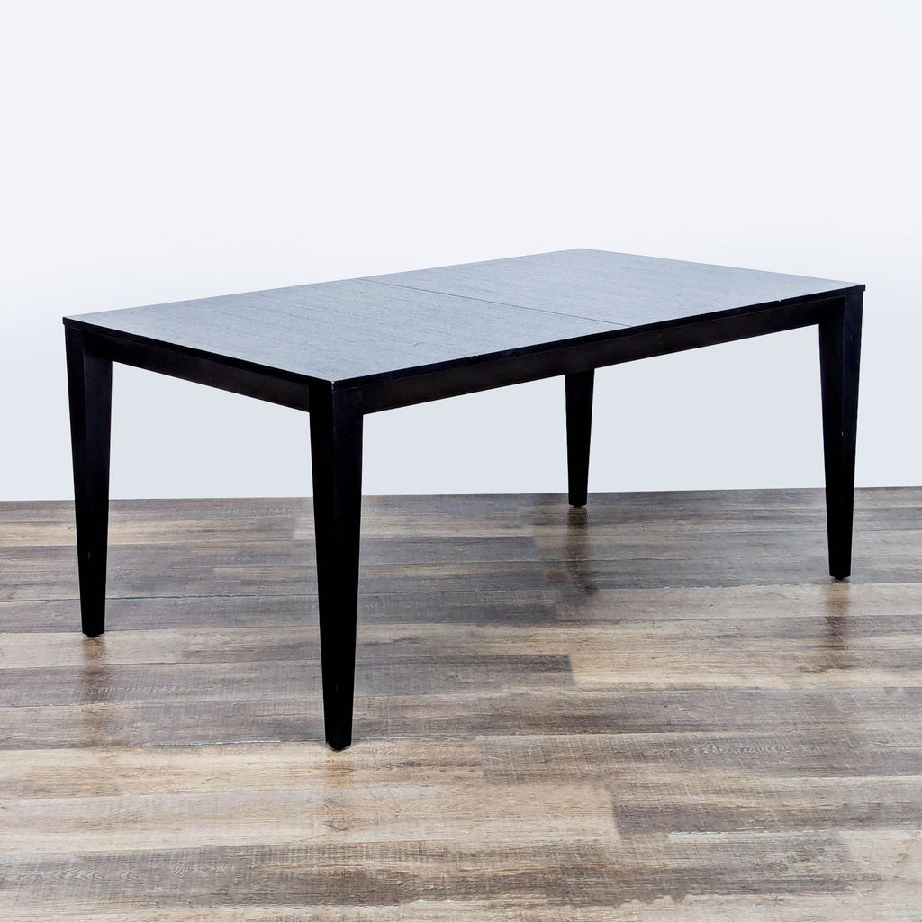 3. Modern ash veneer dining table with sleek black legs by Crate & Barrel, set in a minimalist room.