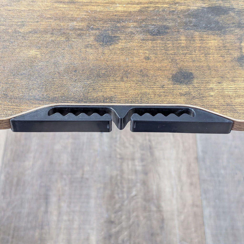 Close-up of Reperch desk’s wood tabletop edge, displaying integrated black plastic groove detail.