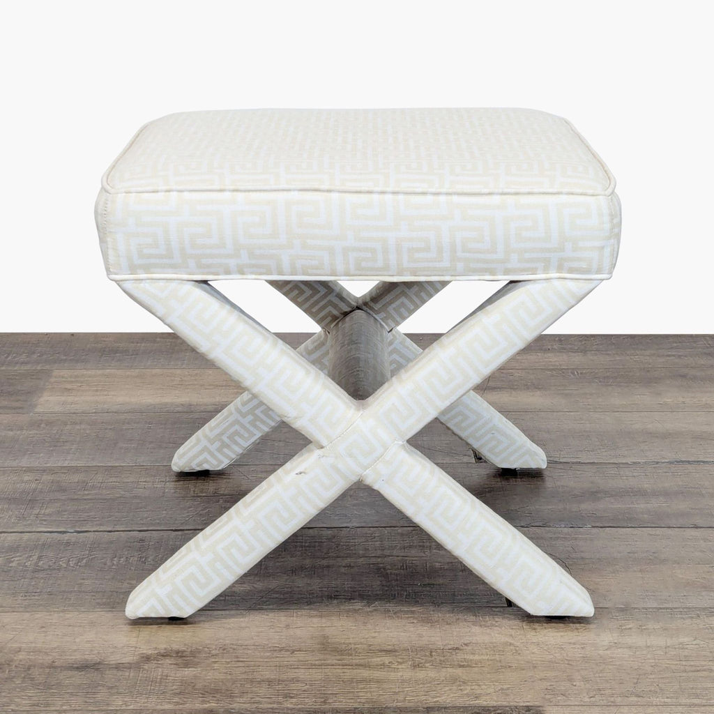 2. Front view of a Lee Industries stool in cream Greek key fabric with crisscrossed legs, on wooden flooring.