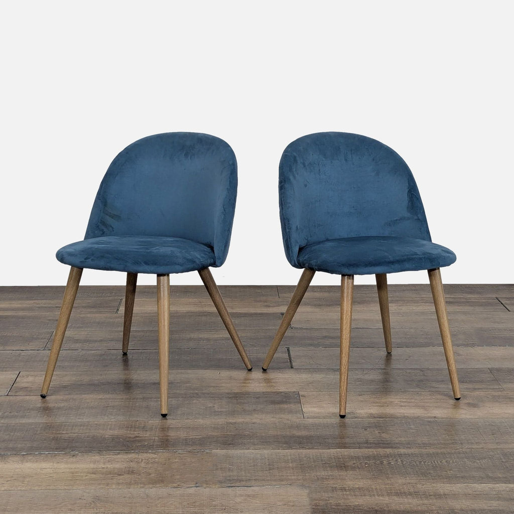 Pair of Reperch blue velvet dining chairs with curved backs and wooden legs on a wooden floor.  