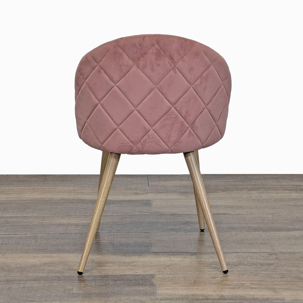 2. Back view of a George Oliver dining chair featuring quilted pink velvet upholstery and tapered metal legs.