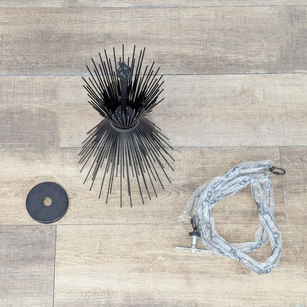 2. Sculptural metal chandelier with starburst rods, shown disassembled with mounting hardware on wooden floor.