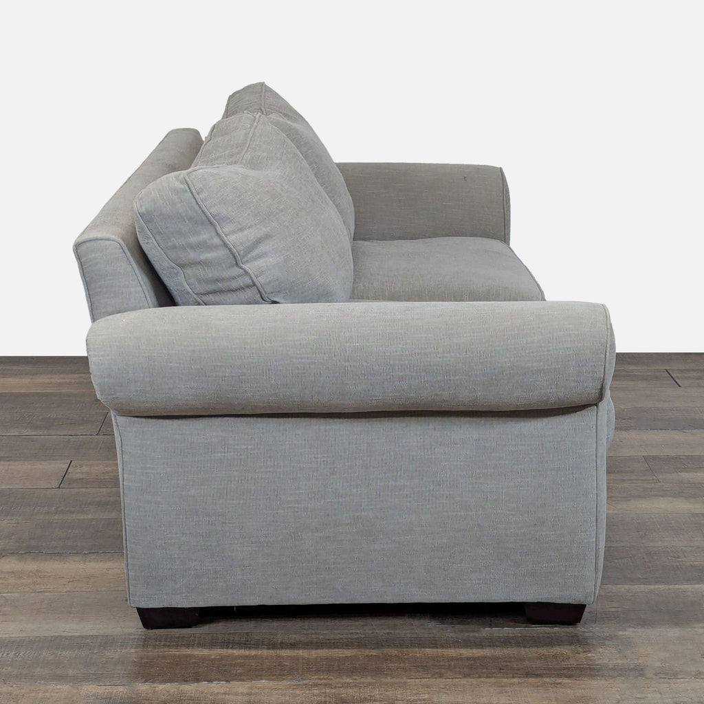 2. Side view of Pottery Barn loveseat showing rolled arm detail and plush cushions with welted trim.