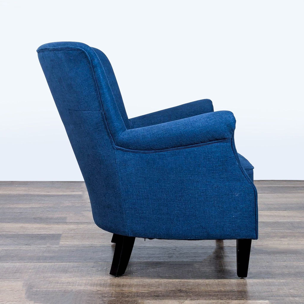 2. Side view showing the rolled arms and angled back of a blue upholstered Pottery Barn lounge chair.