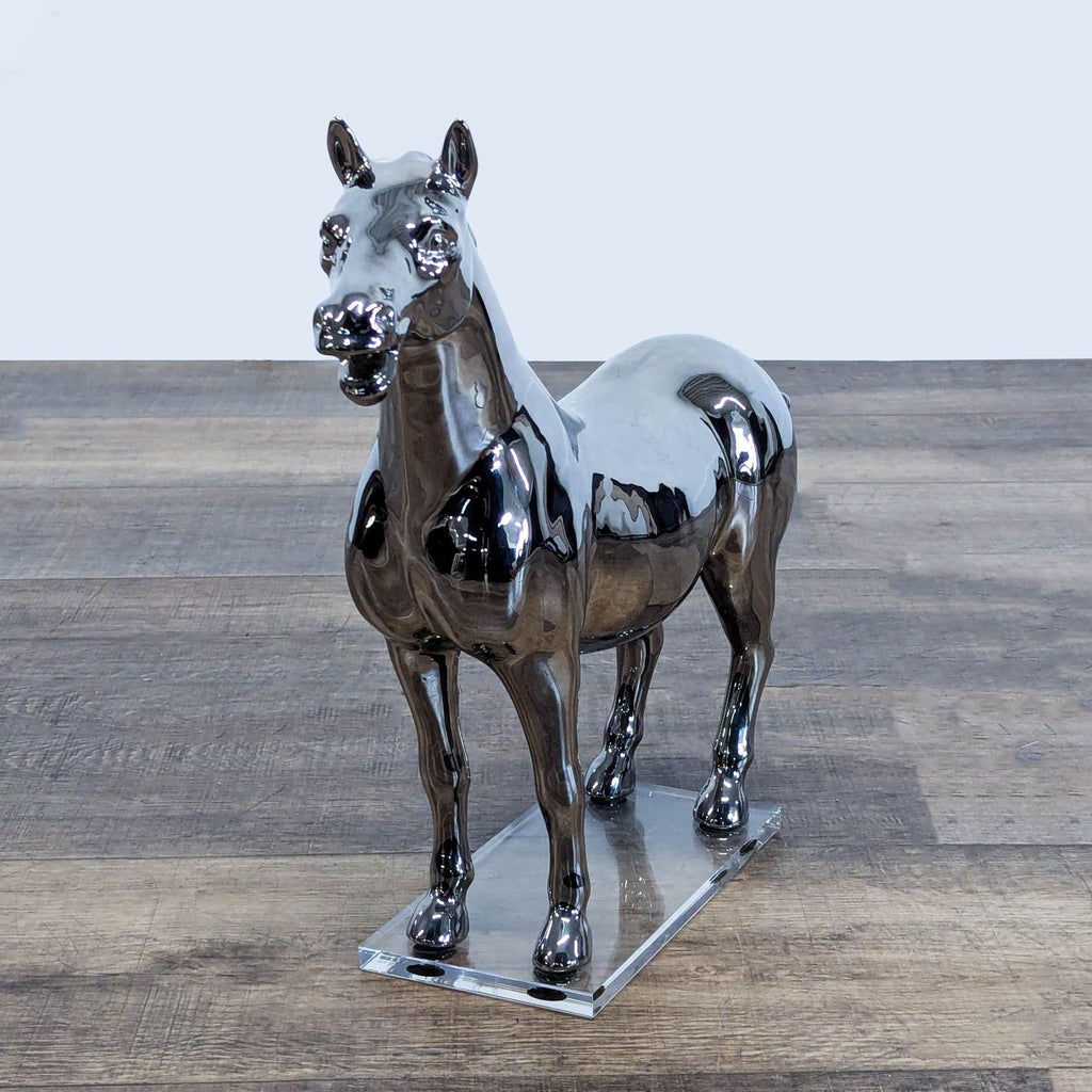 2. Shiny chrome horse statue from West Elm, standing on a transparent acrylic base, sculptural decor.