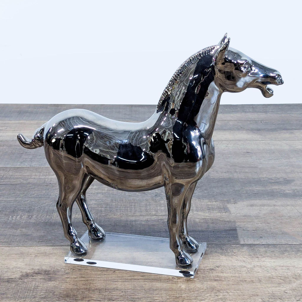 3. West Elm chrome horse sculpture with reflective finish, displayed on a clear acrylic platform.