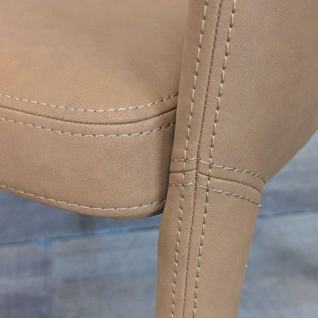 2. Close-up of tan vegan leather upholstery and stitching detail on a Restoration Hardware dining chair.  