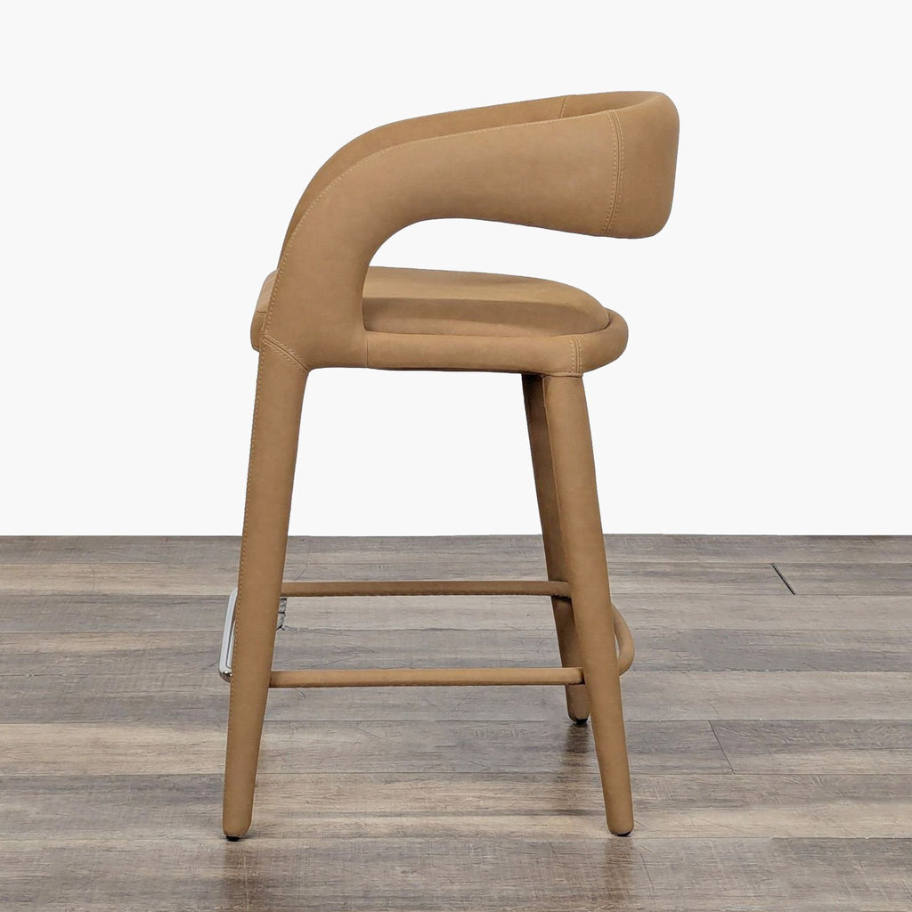 3. Side view of a camel-colored stool with down-swept arms and cushioned seat, featuring sleek, modern style.
