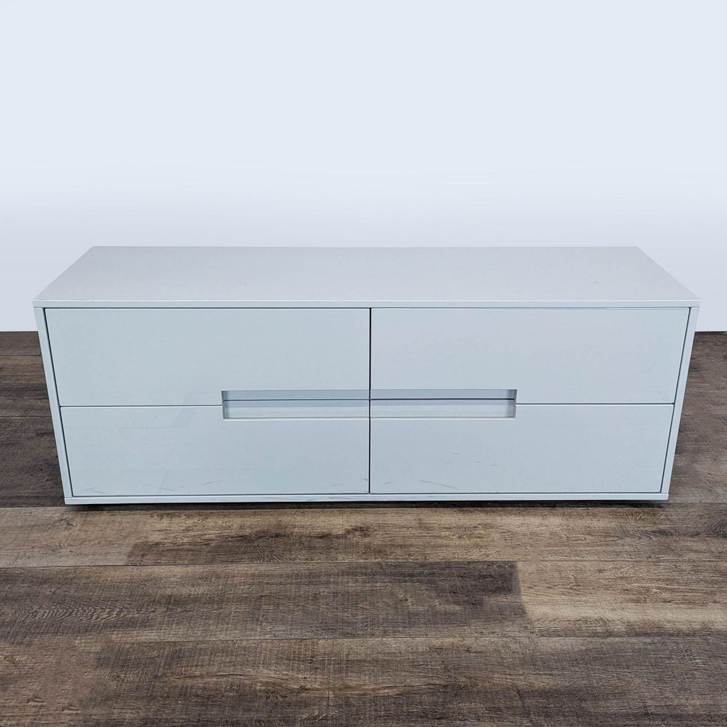 1. CB2 Latitude Low Dresser with four hardware-less drawers and a glossy white finish on a wood floor.