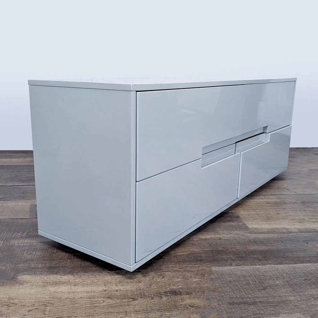 3. Angled view of a sleek, modern white CB2 dresser with four drawers and no visible hardware.