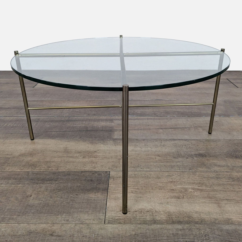 1. Round Reperch coffee table with a clear glass top and slim metallic legs, shown on wood flooring.