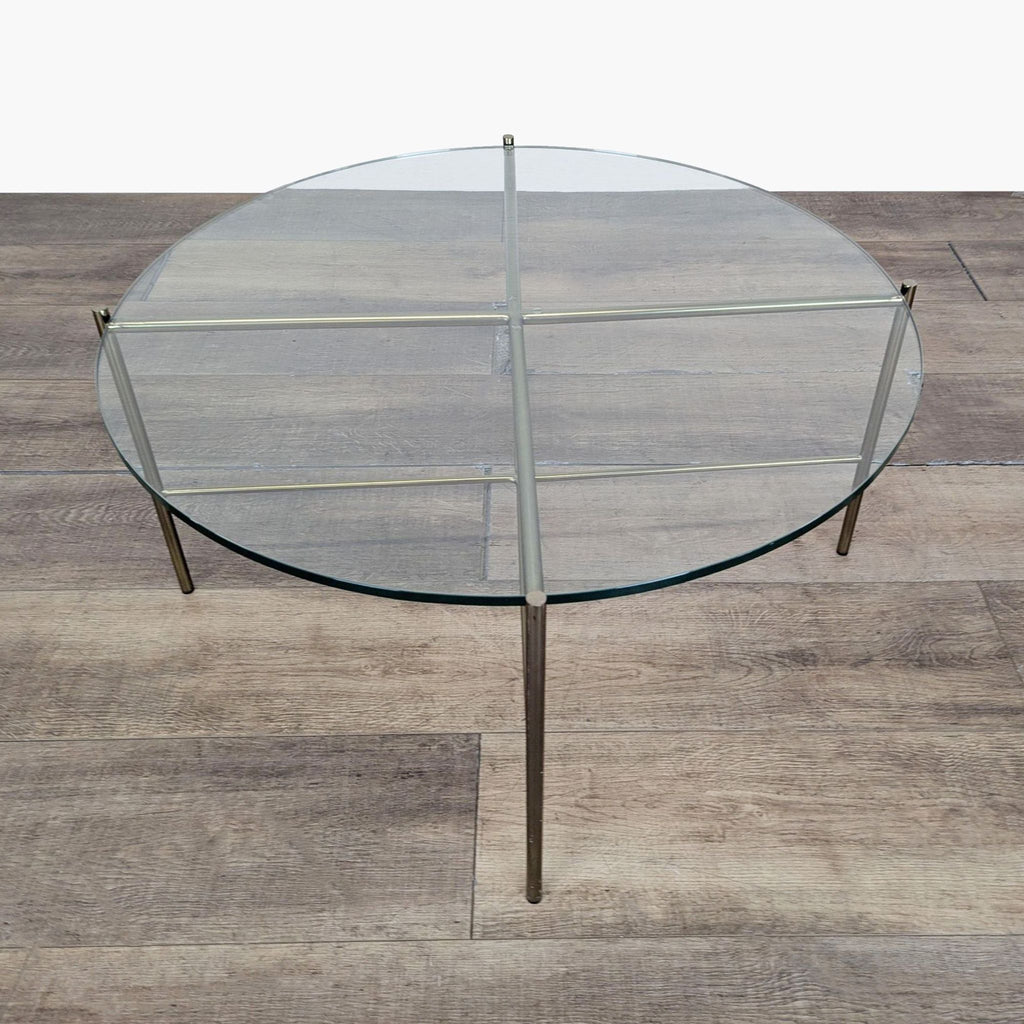 2. Modern circular glass Reperch coffee table featuring a cross metal frame and minimalist design.