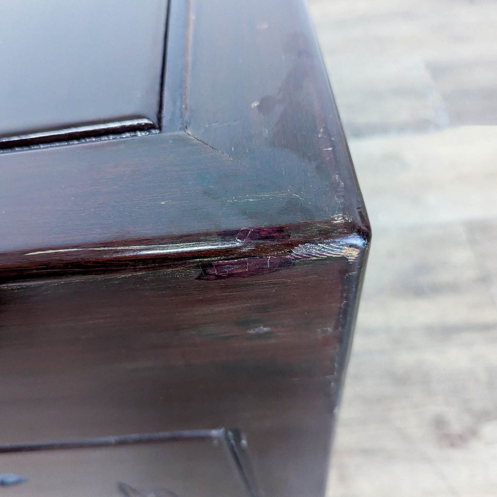 2. Close-up of a Reperch trunk corner showing minor scuffs and wear on the dark wood finish.