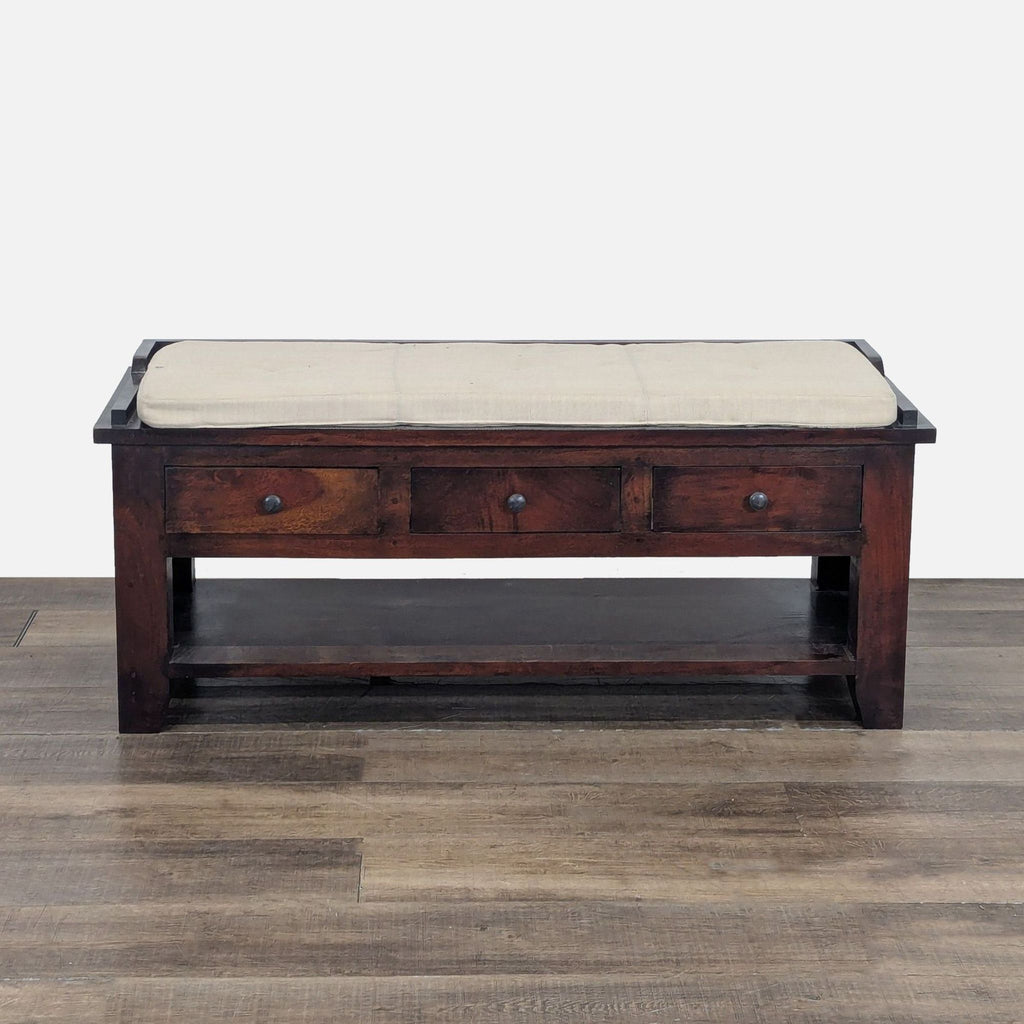 1. Pottery Barn wooden bench with a beige cushion, three drawers, and a lower shelf, placed on a wooden floor.  