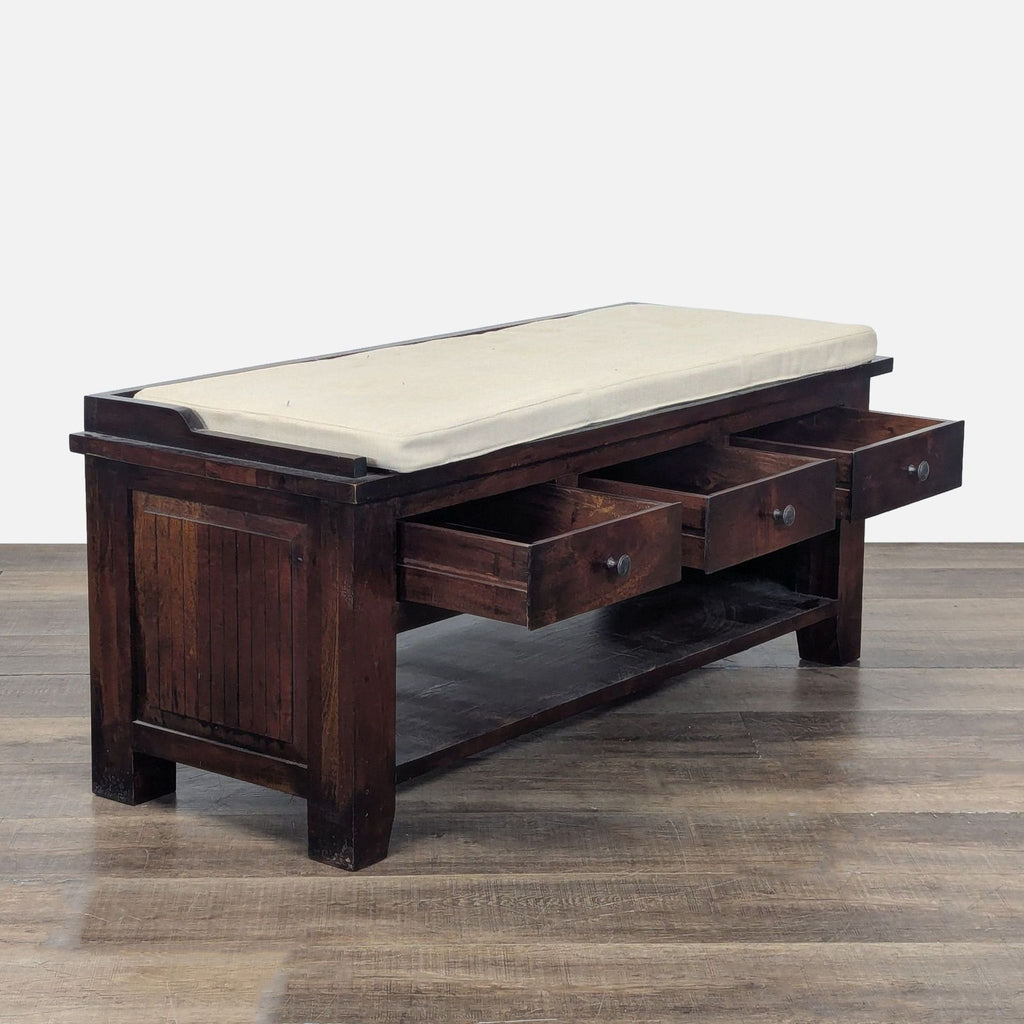 2. Angled view of a Pottery Barn storage bench showing three open drawers and a padded beige seat.  