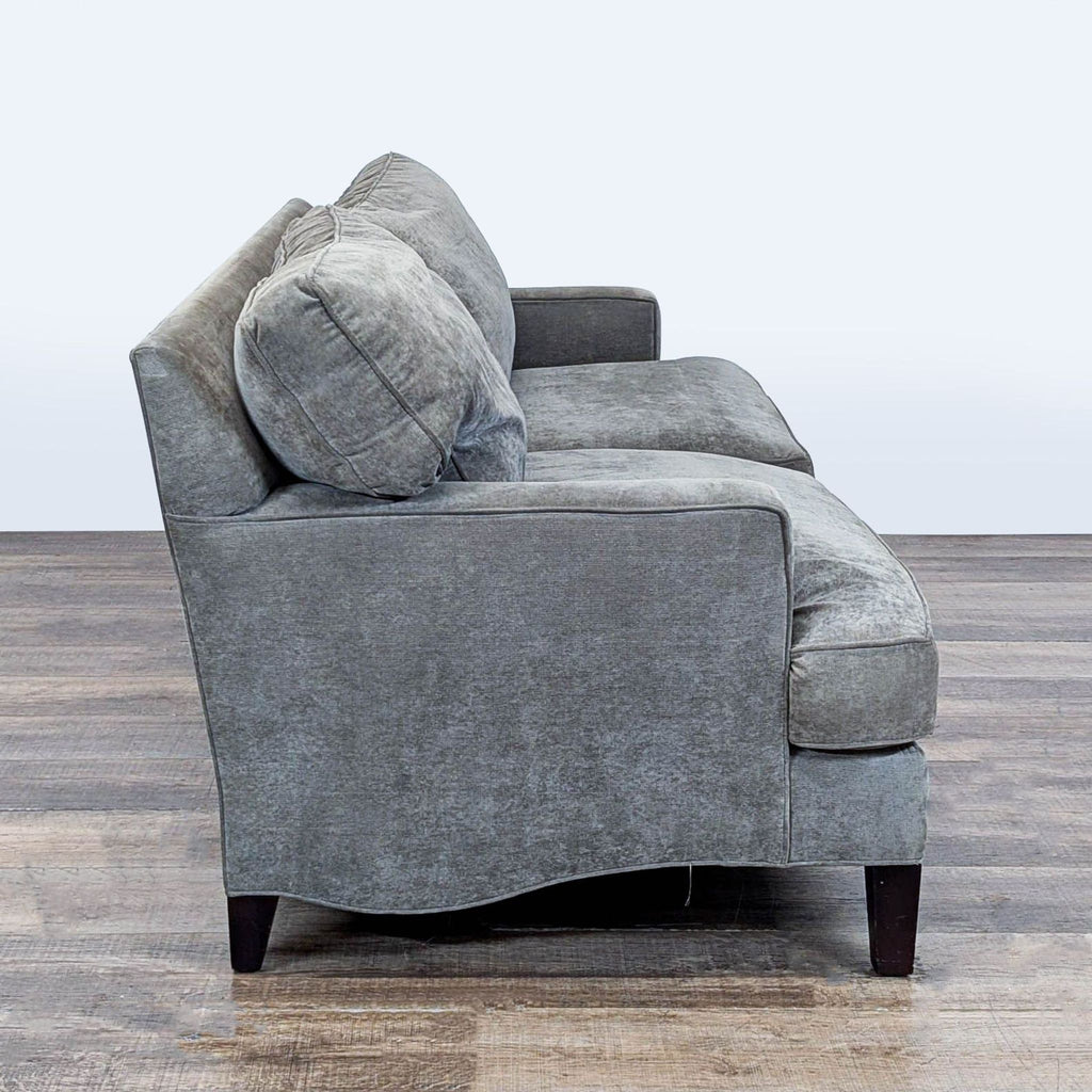 Side angle of a low-profile Room and Board 3-seat sofa showing its loose back and seat cushions.  