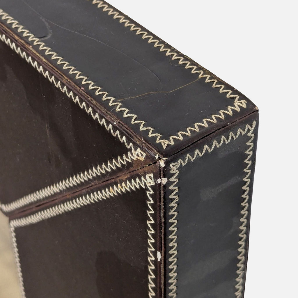 3. Close-up of the Reperch mirror’s corner, highlighting the zigzag stitching on the dark leather frame.