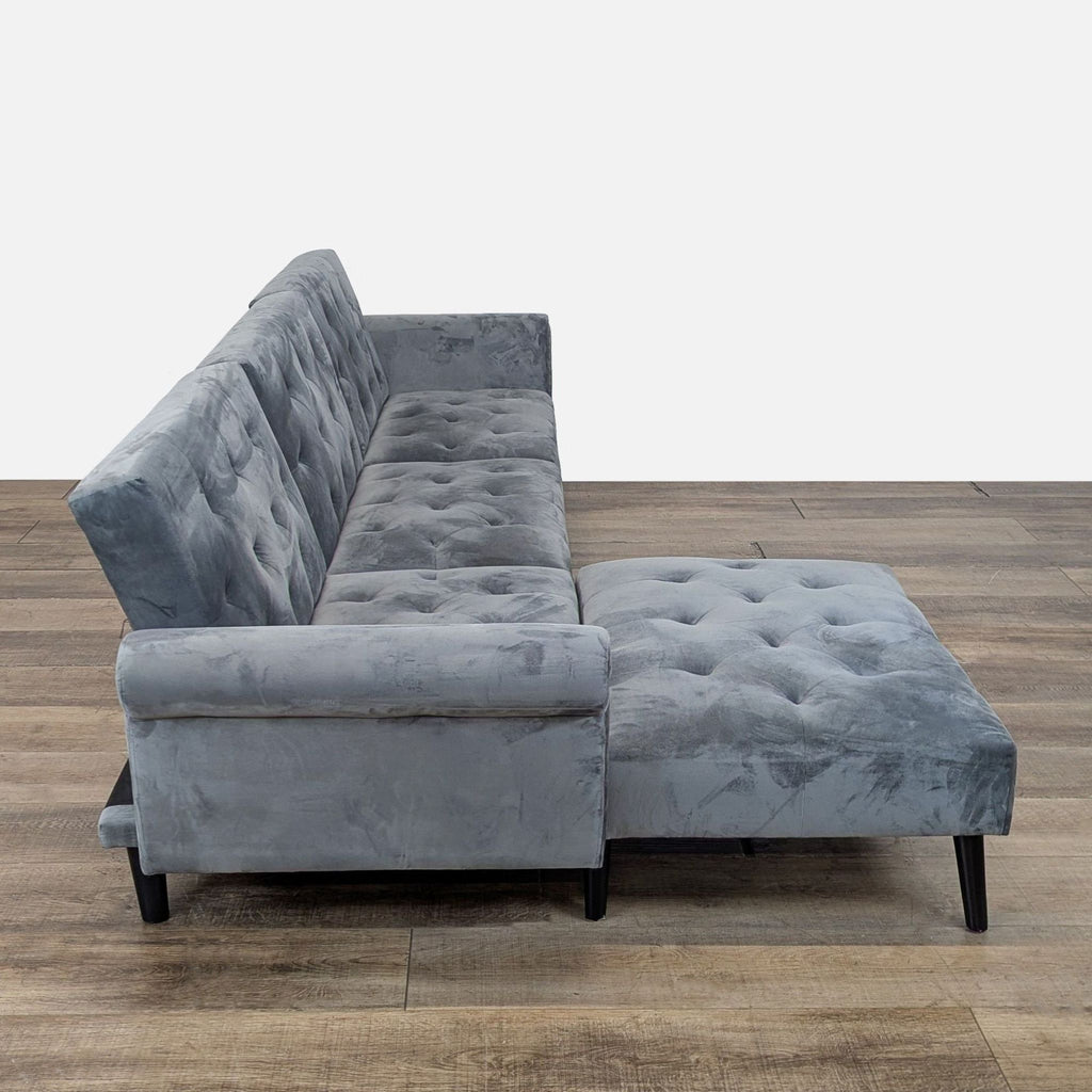 3. Side view of a Reperch gray sleeper sofa with tufted back, rolled arm, and adaptable ottoman.