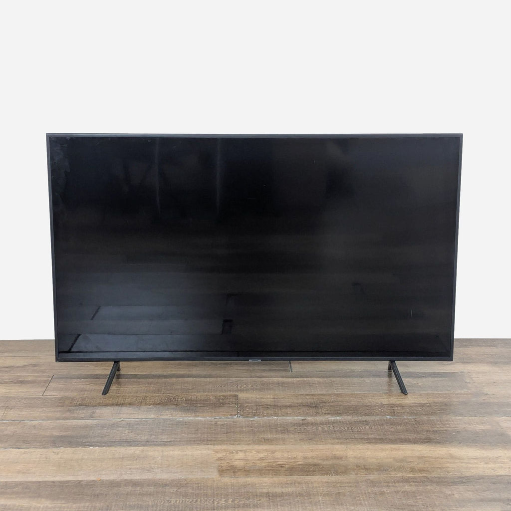1. Front view of a 65-inch Samsung 4K UHD Smart TV with a sleek, minimalist design on a wooden floor.