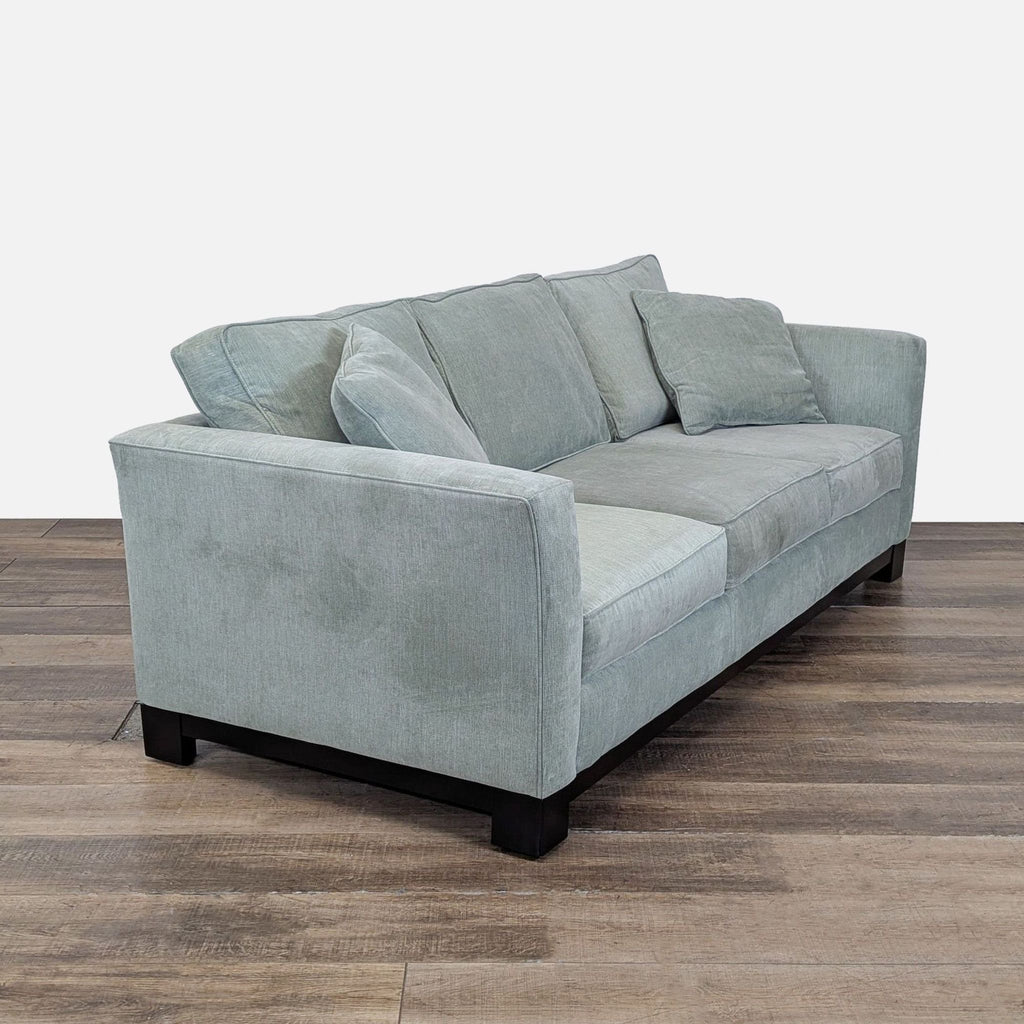 3. Angled view of Reperch 3-seat sofa featuring flared arms, loose cushions, and a dark wooden base.