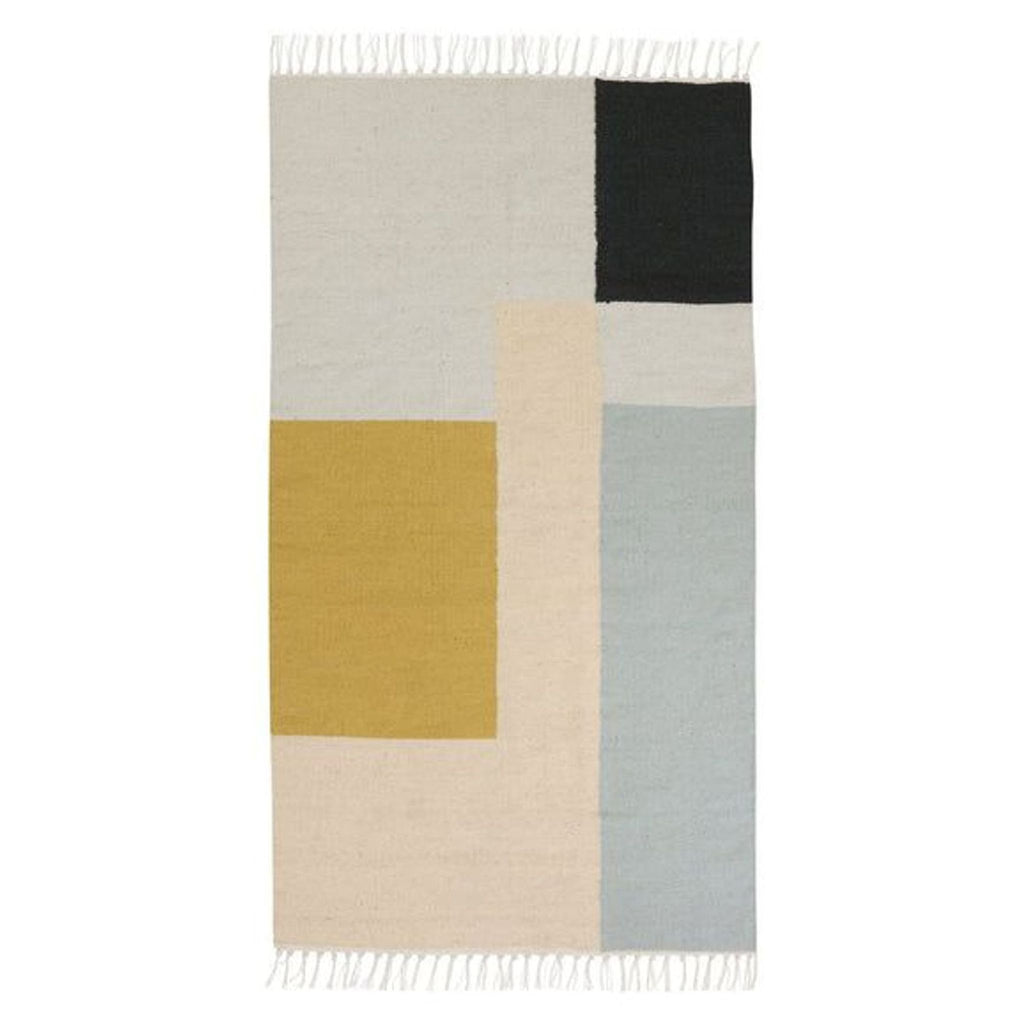 Handmade Ferm Living rug featuring geometric color blocks in soft yellow, blue, cream, and black, with fringed edges.