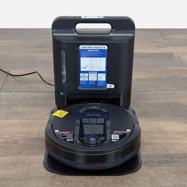 1. Shark robotic vacuum with charging and docking station on wood floor, shown from the front, brand label visible.