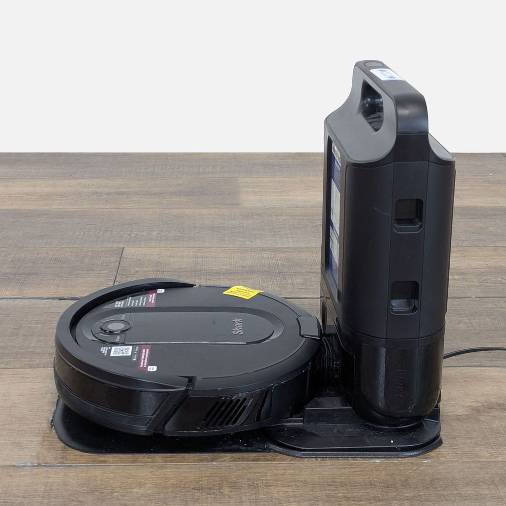 2. Side view of a Shark robot vacuum attached to its charging base, placed on a wooden surface.