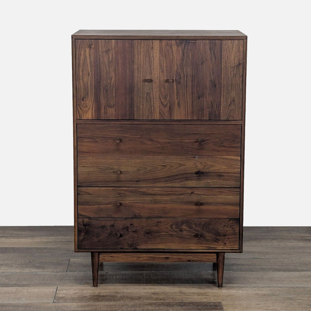 Front view of a walnut Room and Board dresser with four drawers and an upper cabinet on wood floors.