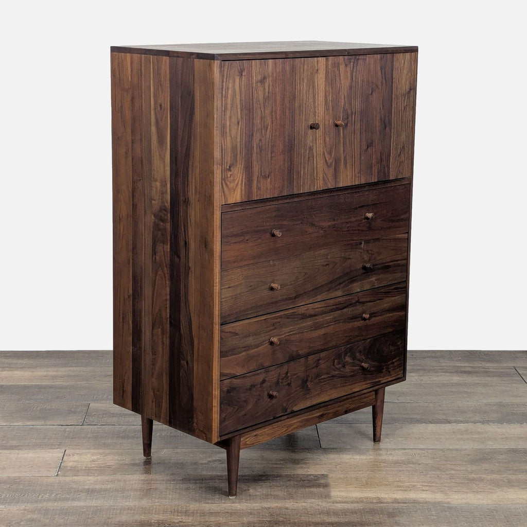 Angled view of a walnut Room and Board dresser showing four drawers and an upper cabinet, standing on tapered legs.