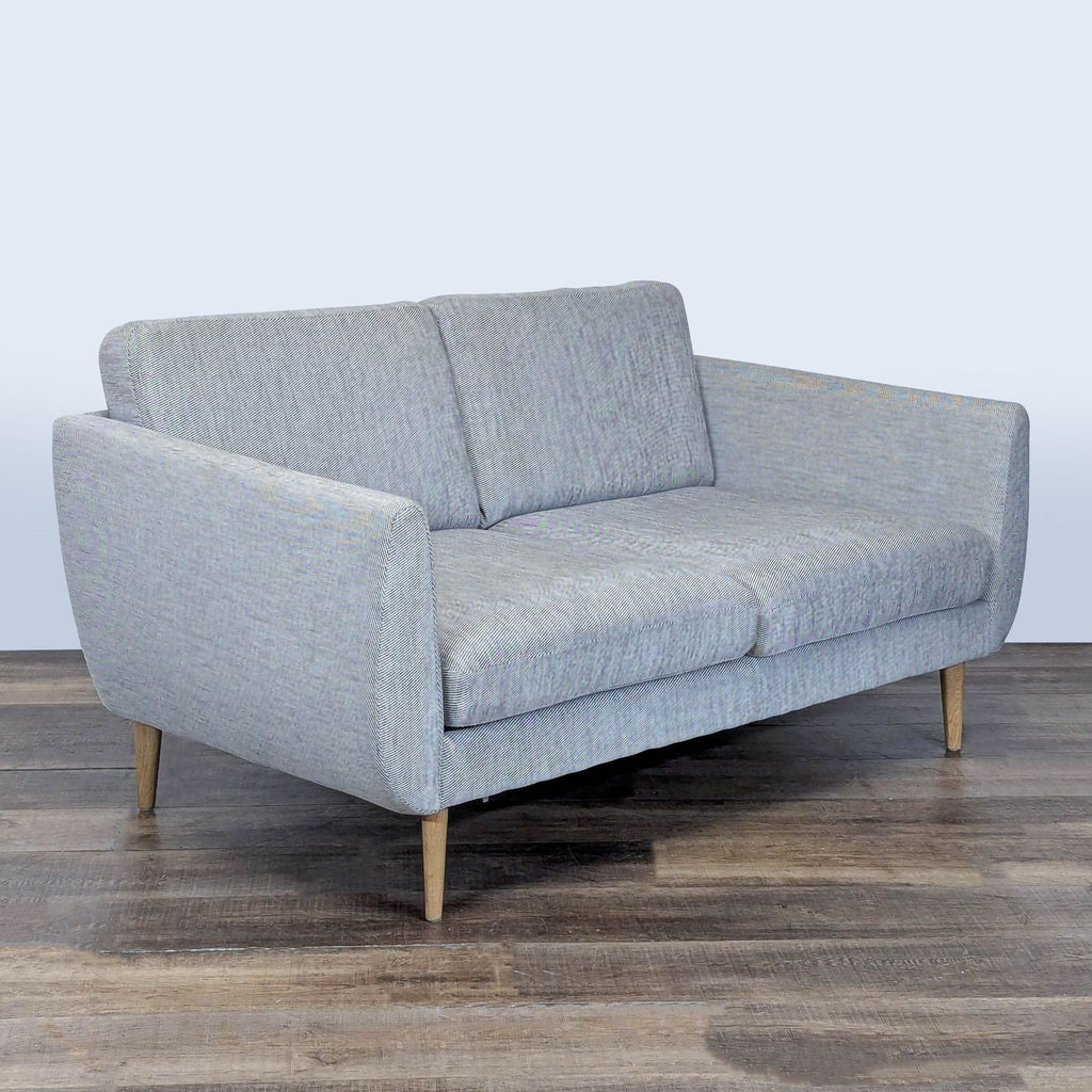 3. Angled view of an Ikea loveseat featuring pocket spring seat cushions, fabric upholstery, and wooden legs.