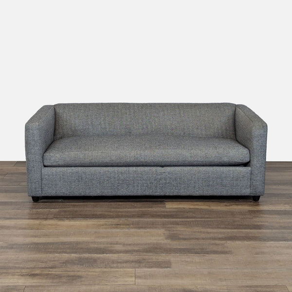 1. Grey CB2 sleeper sofa with deep single cushion seat, shown on a wood floor against a plain background.