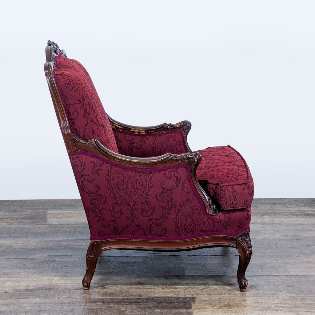 2. Side view of a Reperch lounge chair, showing carved wood arms and burgundy damask baroque fabric.